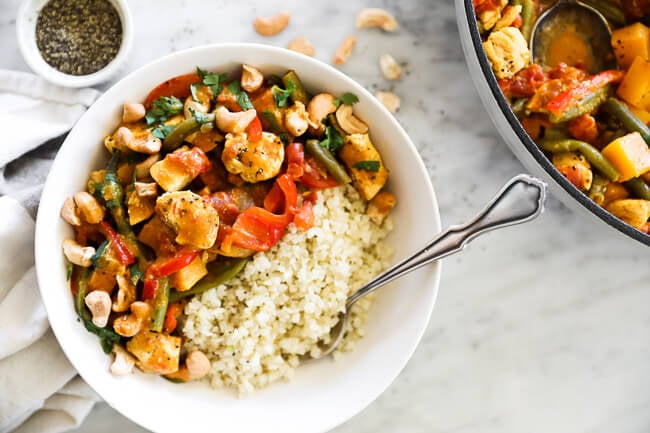 Horizontal overhead image of butternut squash curry served in a bowl with cauliflower rice and fork. 