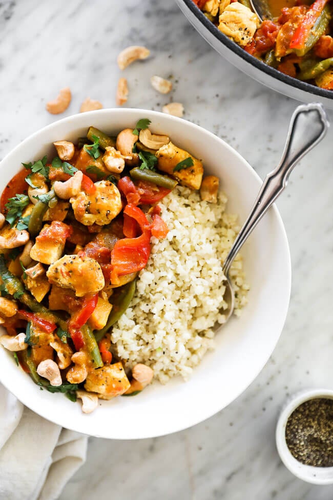 Vertical overhead image of butternut squash curry served in a bowl with cauliflower rice and a fork. 