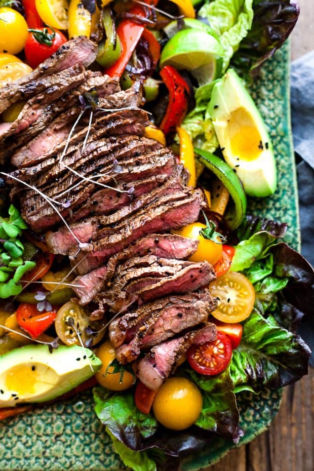 Sliced steak on top of veggies in a salad
