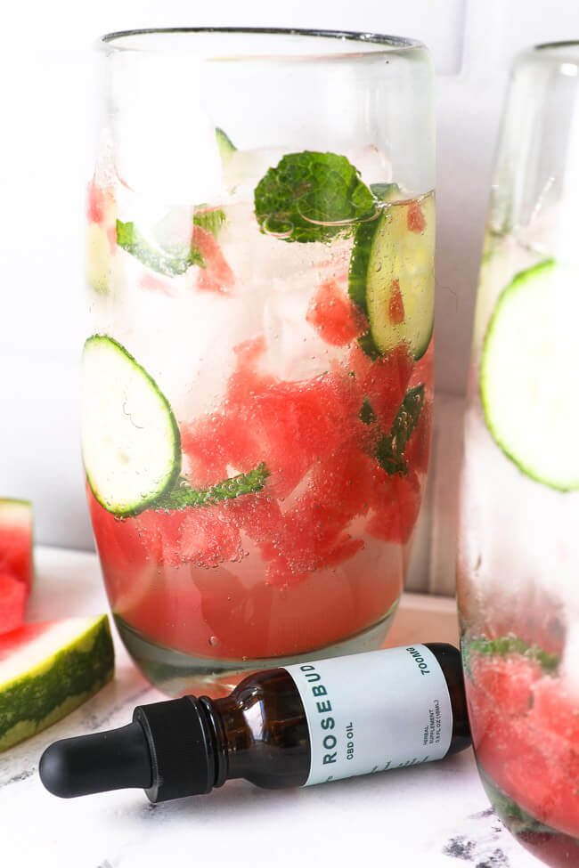 Watermelon mojito mocktail with cbd bottle in the foreground. 
