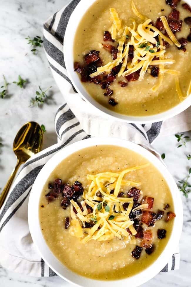 Two bowls of celeriac soup, topped with bacon, shredded cheese and fresh thyme. 