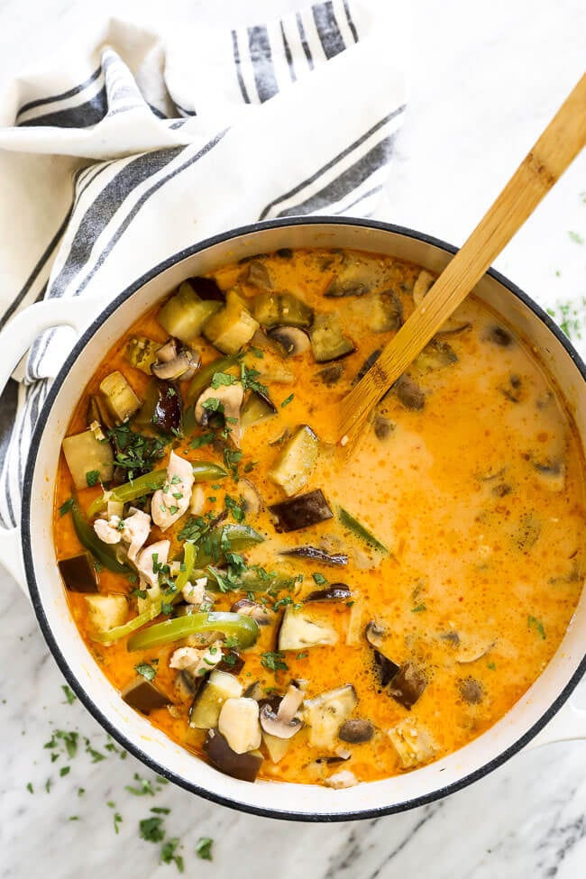 Chicken coconut curry soup in pot with spoon overhead vertical image
