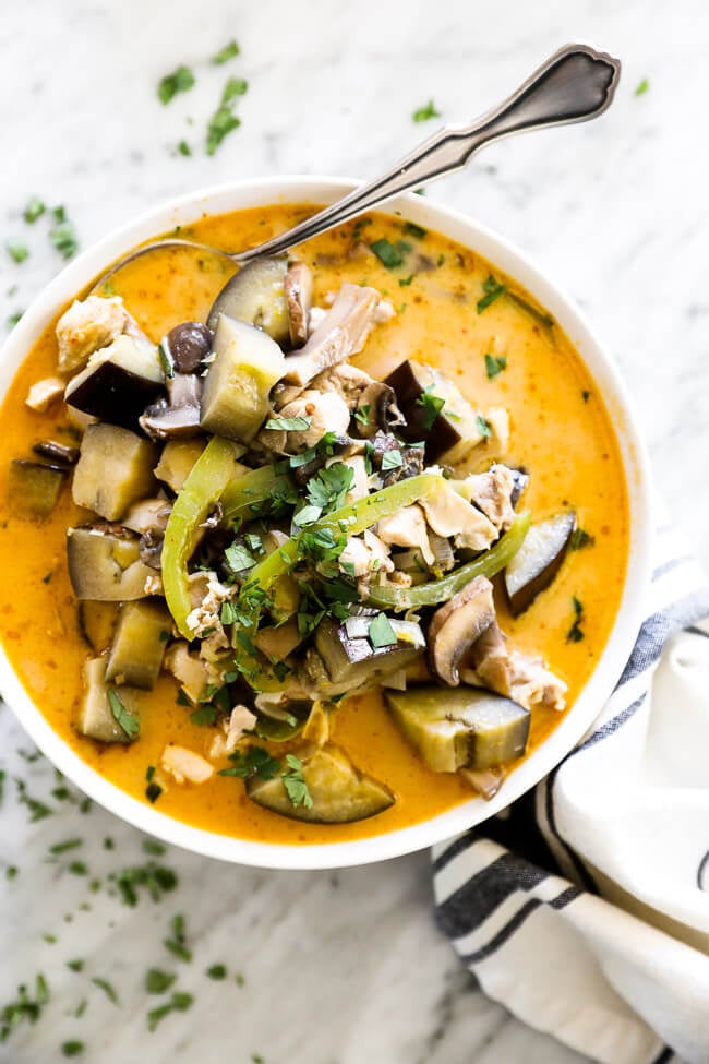 Chicken coconut curry soup in bowl with spoon at top overhead vertical image