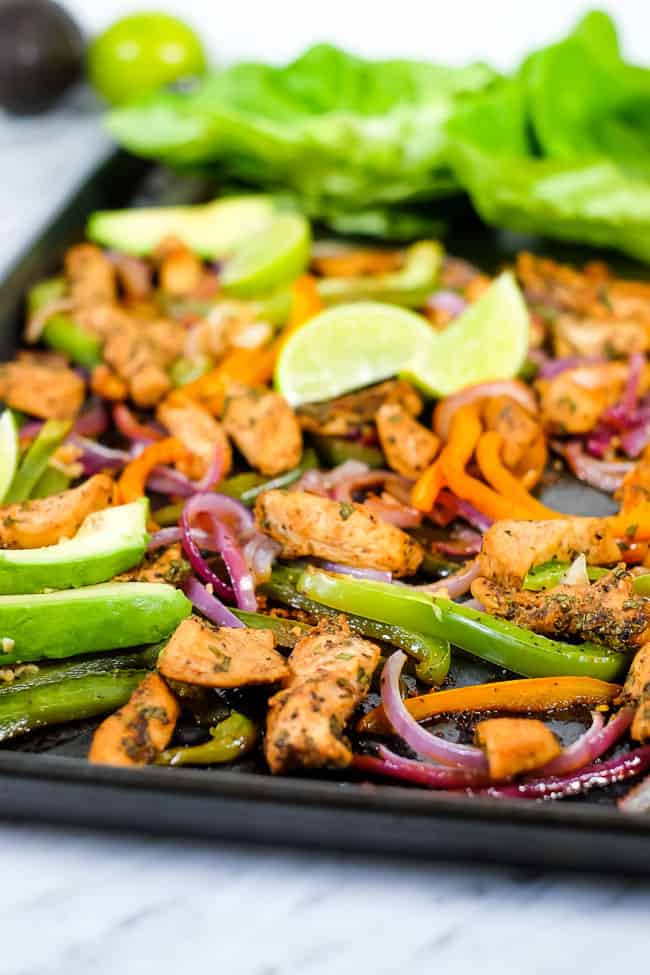 Sheet pan chicken fajita bake with avocado, lime, cilantro and butter lettuce on sheet pan. 