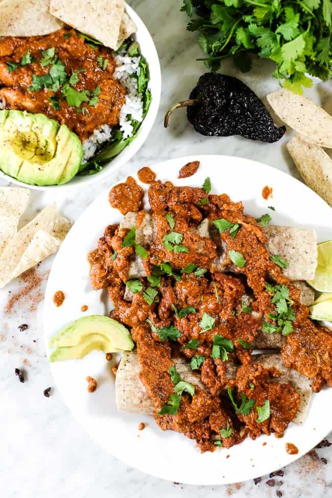 Chicken mole recipe used in enchiladas and topped with more chicken mole, avocado and chopped cilantro. 