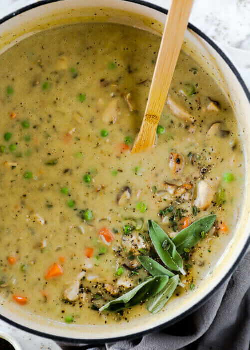 Creamy chicken pot pie soup in a pot with spoon coming out