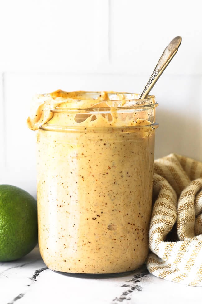 Straight on shot of a mason jar full of chipotle aioli with spoon sticking out