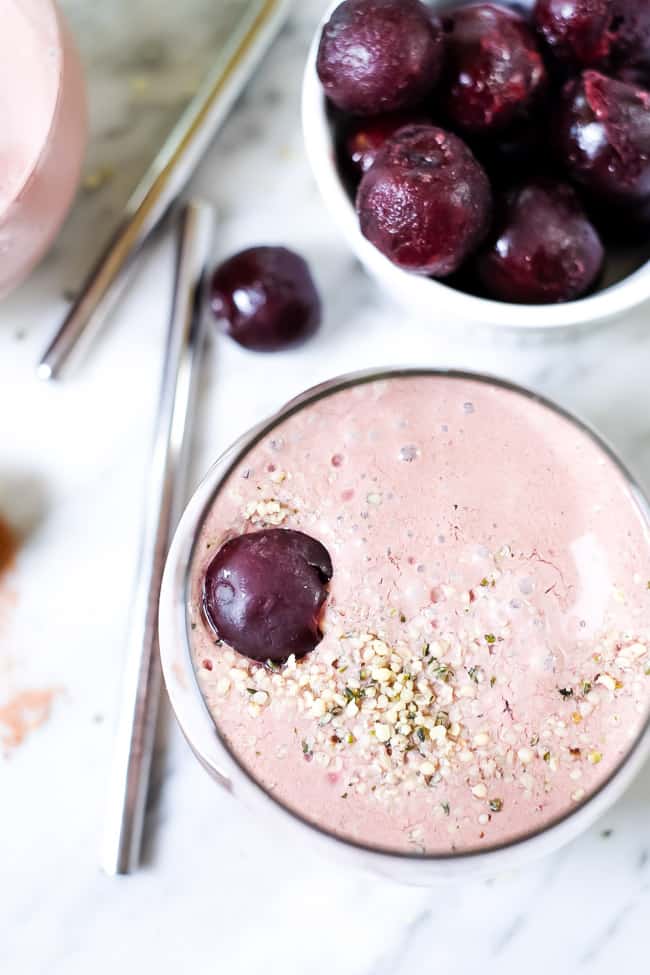 Chocolate cherry smoothie in glass with hempseed and cherry topping. 