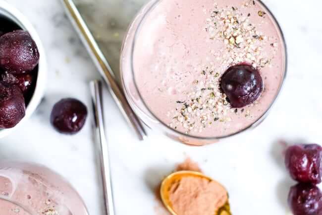 Chocolate cherry smoothie in glasses with hempseed and cherry topping. 