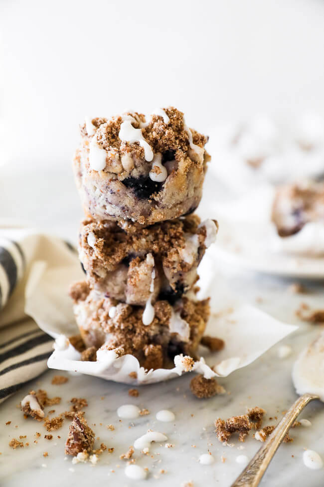 Vertical straight on image of stack of three coffee cake muffins with coconut butter drizzle cascading down the side. 