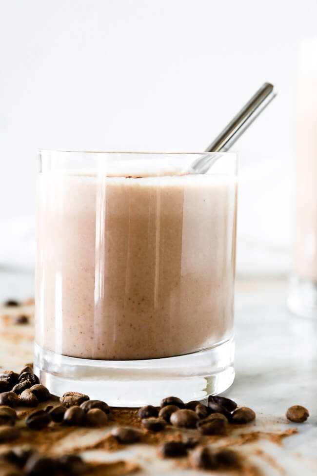 Vertical straight on image of coffee smoothie in a glass a stainless steel straw. 