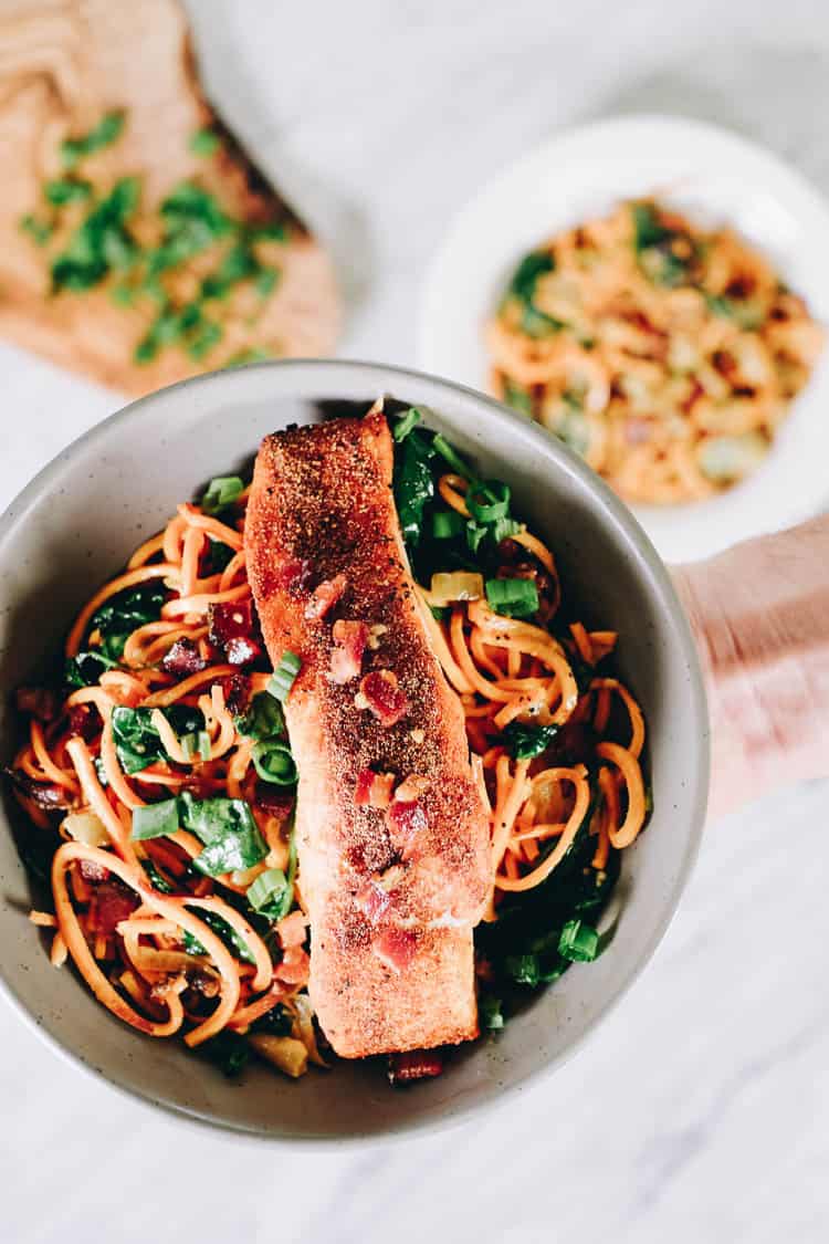 Creamy salmon sweet potato noodle bowls overhead hand holding bowl up