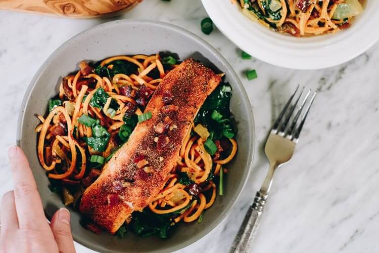 Creamy salmon sweet potato noodle bowls horizontal with hand on bowl