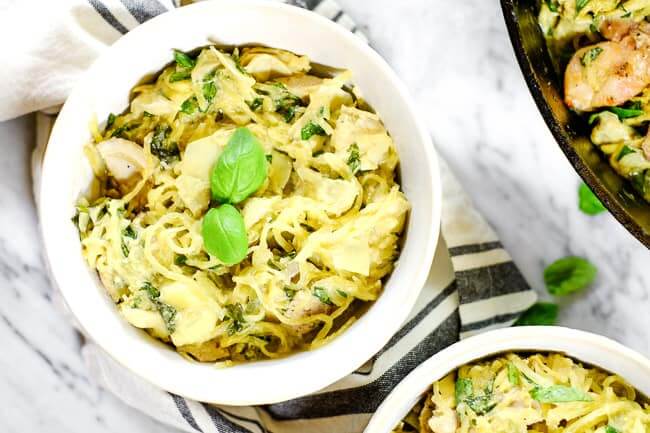 Creamy chicken casserole served in bowl with fresh basil garnish and striped napkin. 