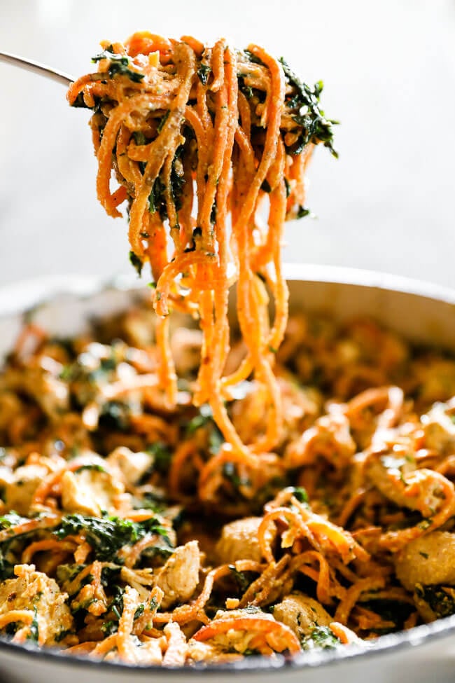 Big forkful of creamy chicken sweet potato noodles coming out a pan vertical image