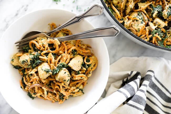 Creamy chicken sweet potato noodles in a bowl with fork and spoon horizontal image
