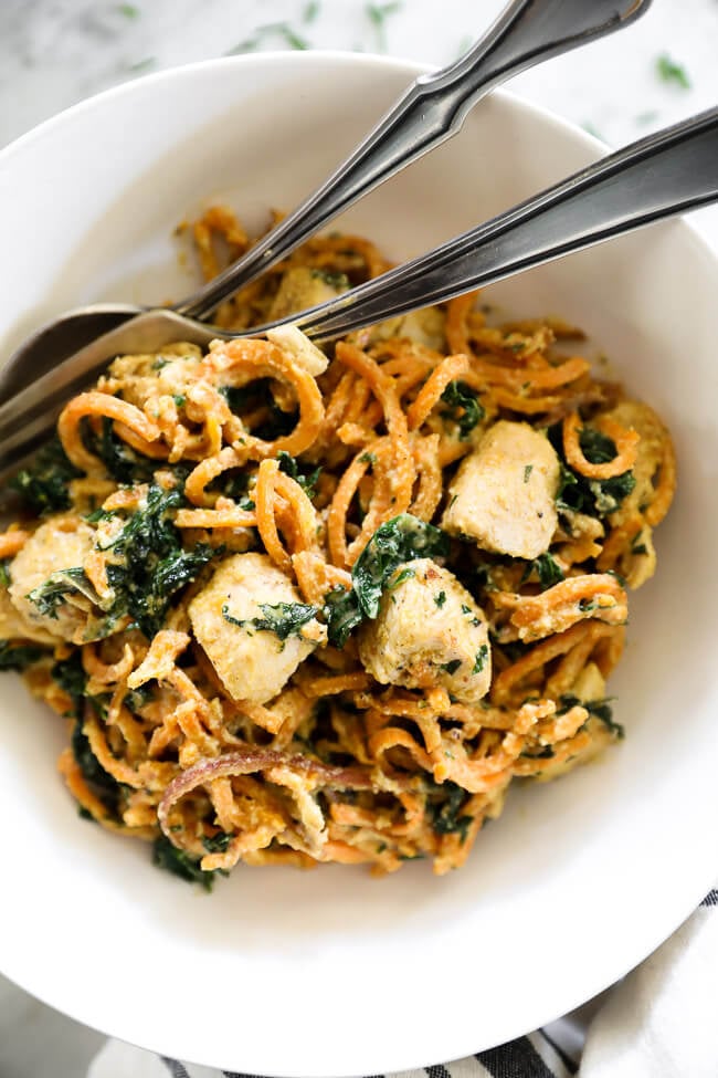 Overhead shot of creamy chicken sweet potato noodles in a bowl with fork and spoon vertical image