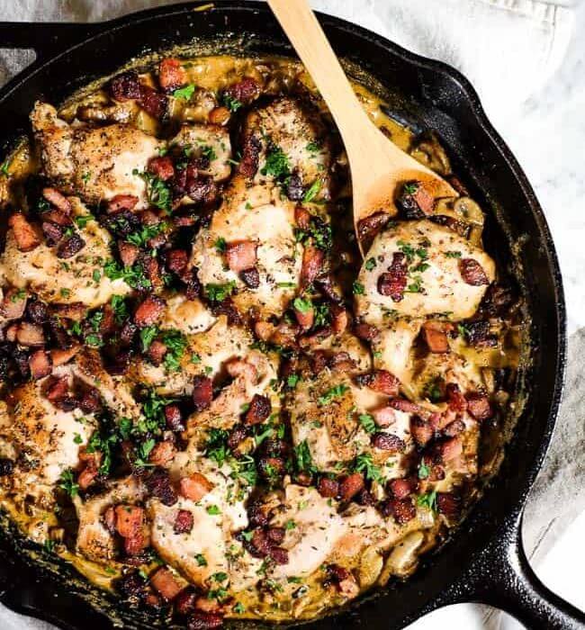 Featured image for essential keto chicken recipes of chicken thighs in a cast iron pan with creamy sauce and bacon bits