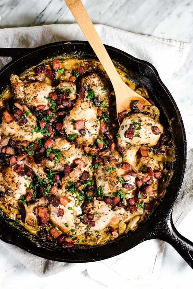 Featured image for essential keto chicken recipes of chicken thighs in a cast iron pan with creamy sauce and bacon bits