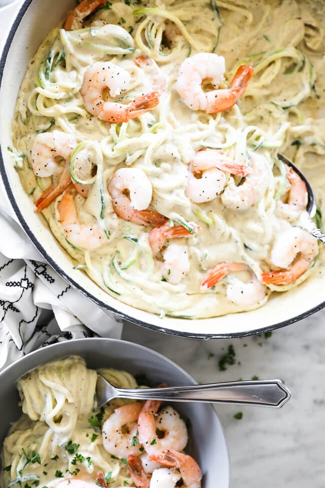 Close up image vertical overhead image of creamy garlic shrimp in skillet with some also served in a bowl. 