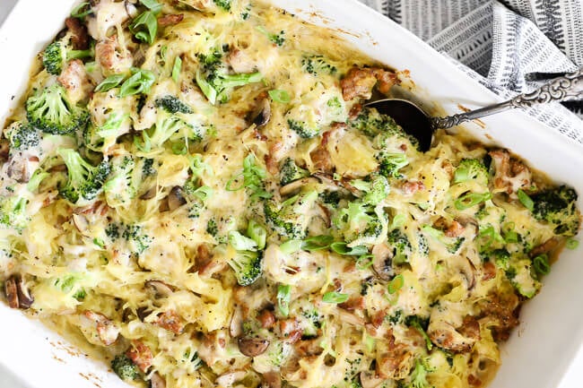 Horizontal image of spaghetti squash casserole in a large dish with serving spoon. 