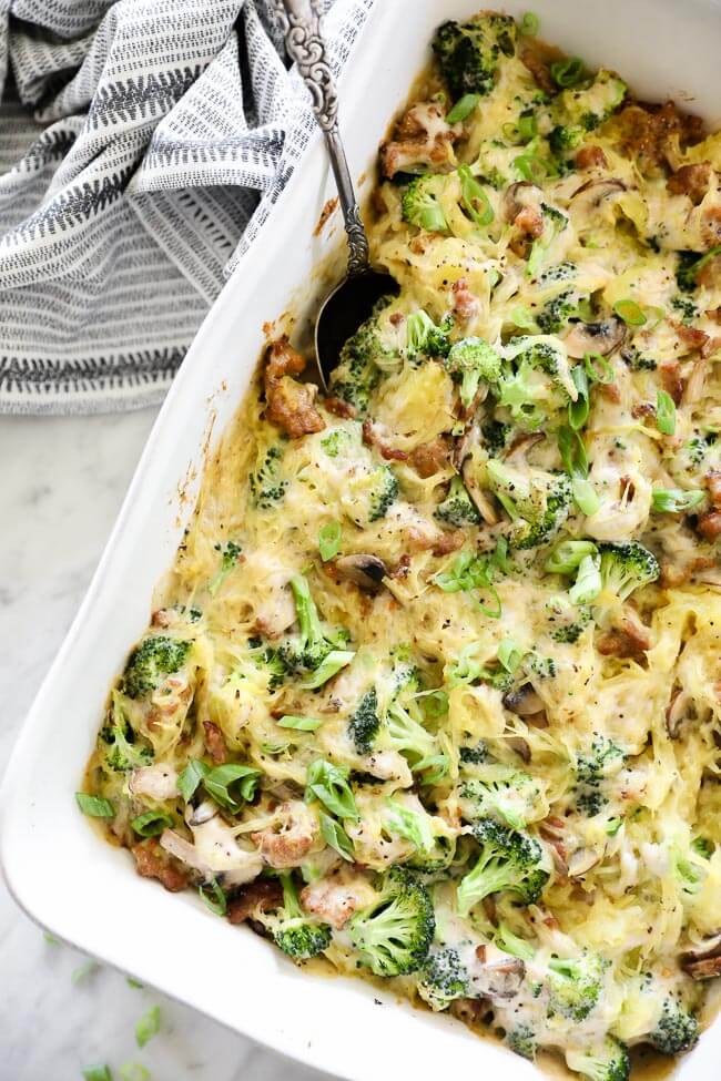 Overhead vertical image of casserole dish filled with creamy garlic spaghetti squash and a serving spoon. 