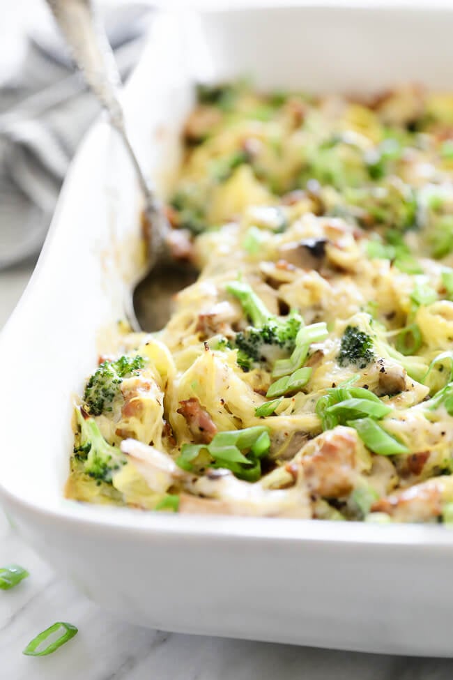 Angled close up image of spaghetti squash casserole in dish with serving spoon. 