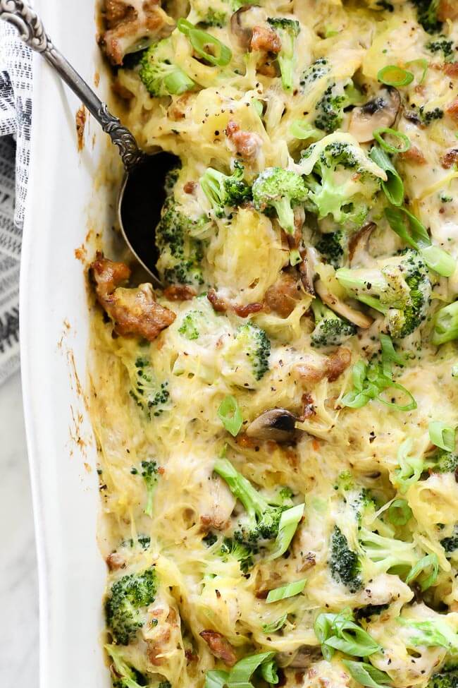 Close up vertical overhead image of spaghetti squash casserole in dish with serving spoon. 