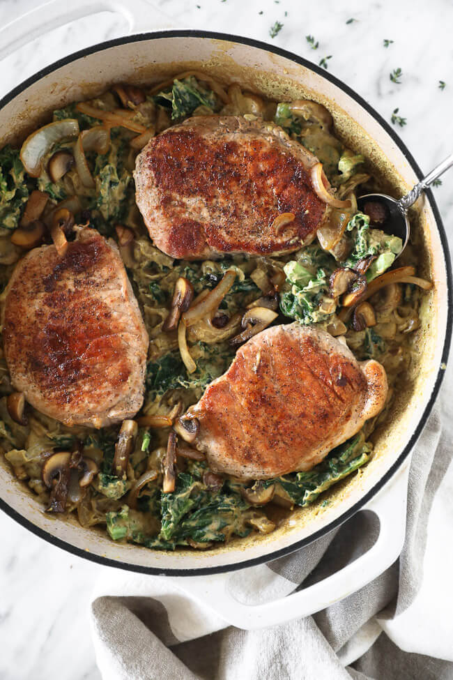 Vertical overhead image of pork chops in a creamy sauce in a skillet with a serving spoon. 