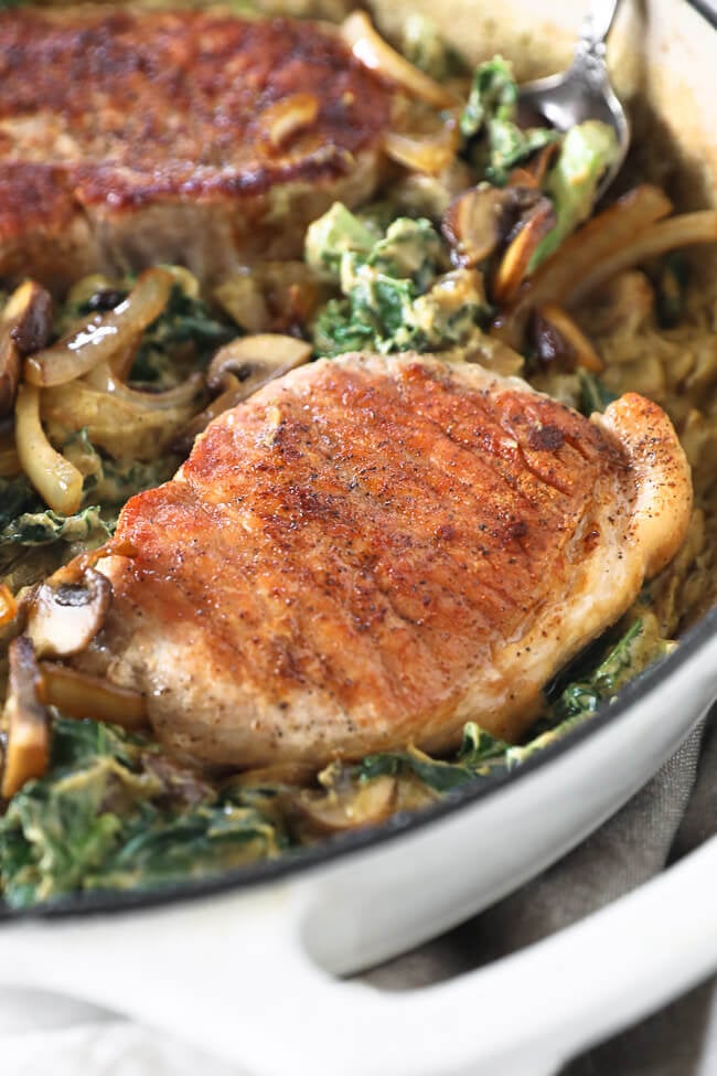 Vertical angled close up image of one pork chop in the skillet. 