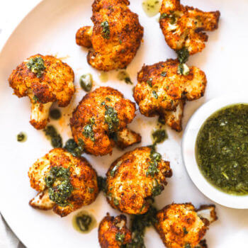 Crispy air fryer cauliflower on a white plate with chimichurri sauce ont top