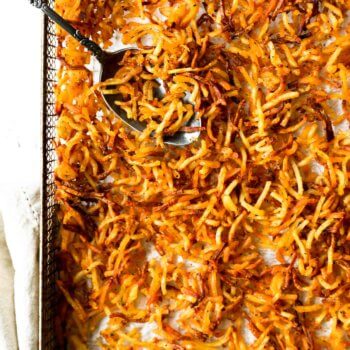 Close up overhead of air fryer hash browns in a basket with spoon