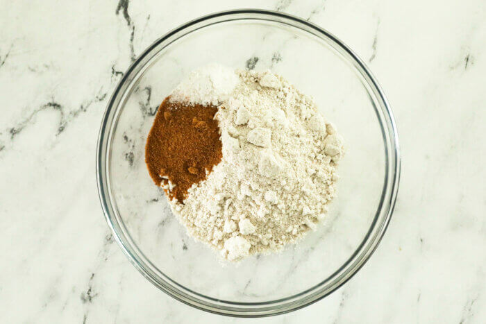 A mixing bowl with all of the dry ingredients to make oat flour waffles before whisking together.