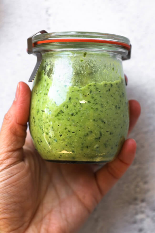 Image of holding a jar of pesto sauce. 