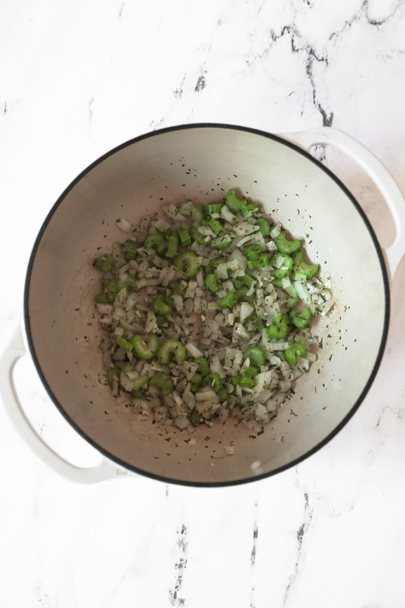 Diced onion, chopped celery, minced garlic and seasonings cooked in a dutch oven.