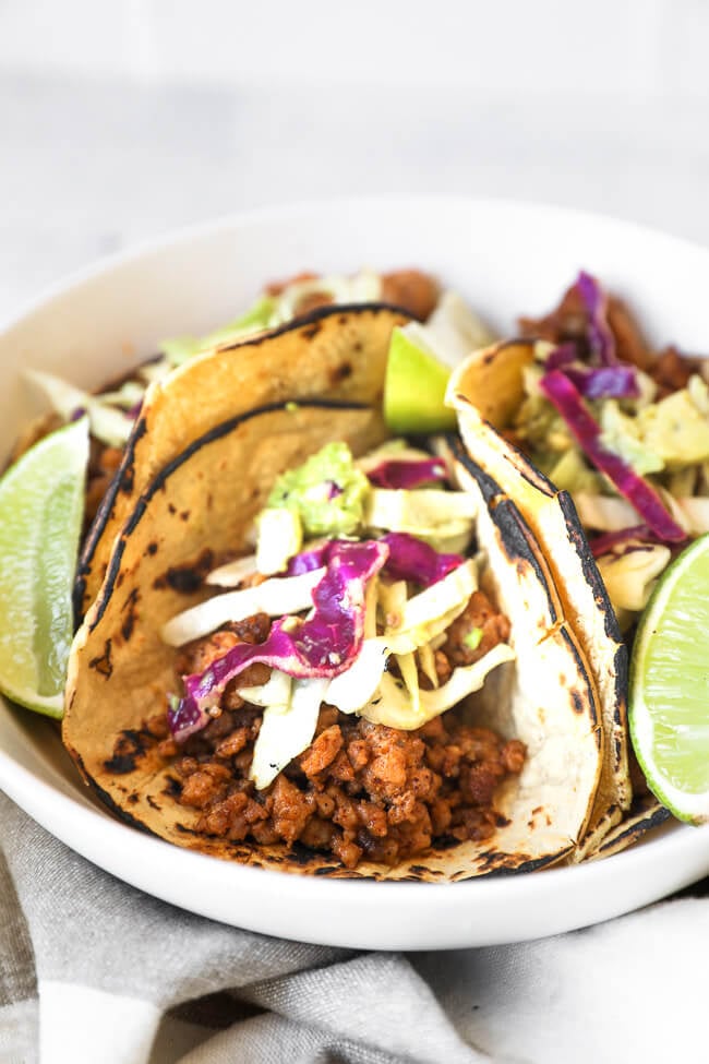 Close up straight on image of one of the ground pork tacos with cabbage and avocado slaw on top. 