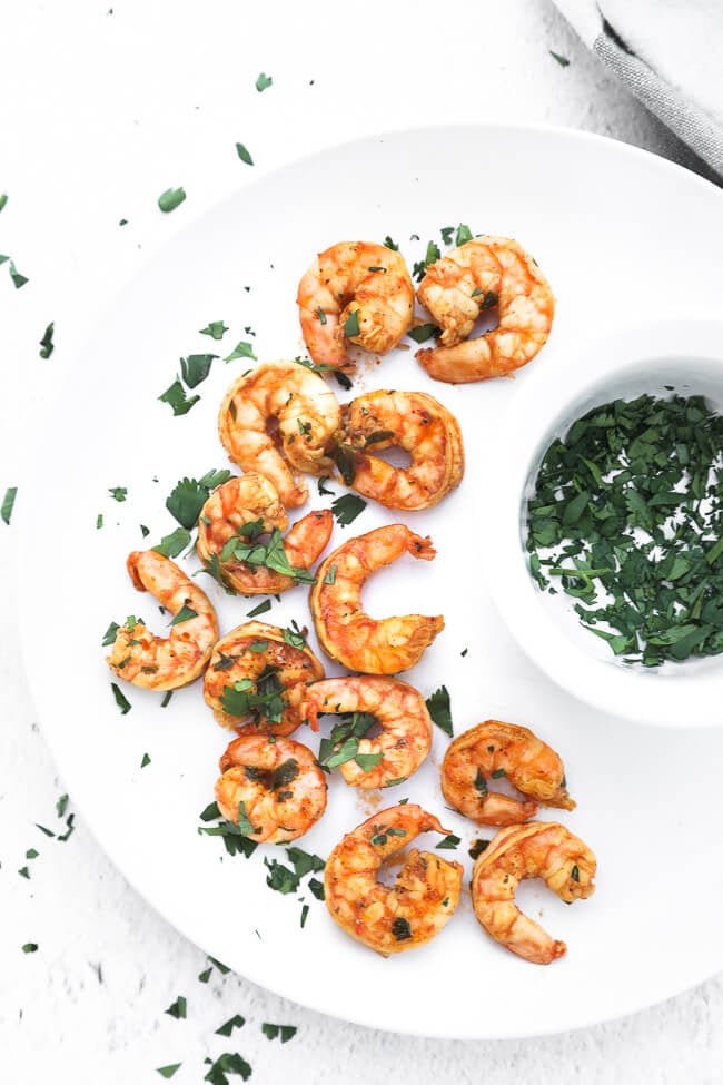 Chili lime shrimp on a plate with chopped cilantro on top and on the side.