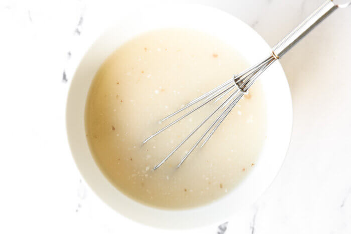 Chicken broth and tapioca starch mixed in a bowl with whisk sticking out