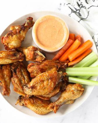 Plate of air fryer chicken wings with carrots, celery and dipping sauce