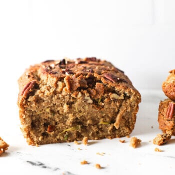 Straight on shot of a loaf of zucchini bread with a couple of pieces sliced off to see the texture of the bread.