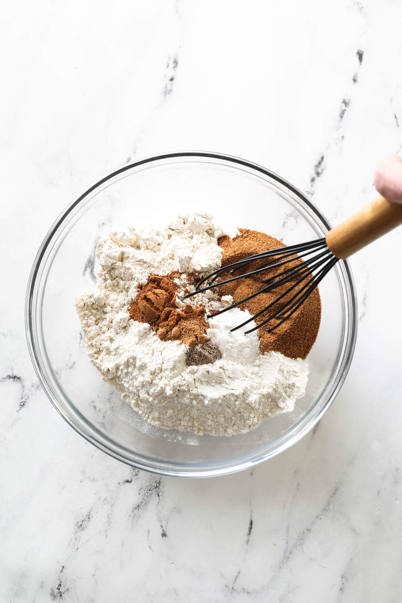 All of the dry ingredients for making zucchini bread in a mixing bowl with a whisk.