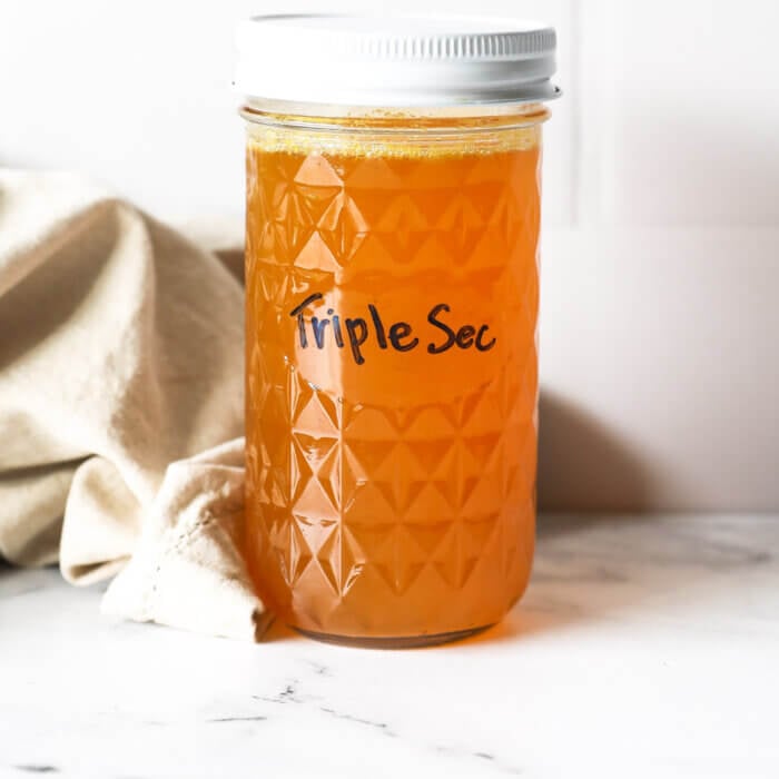 A jar of homemade triple sec with a white cap