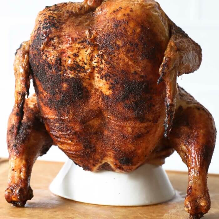 Cooked Traeger beer can chicken on a roaster stand standing upright