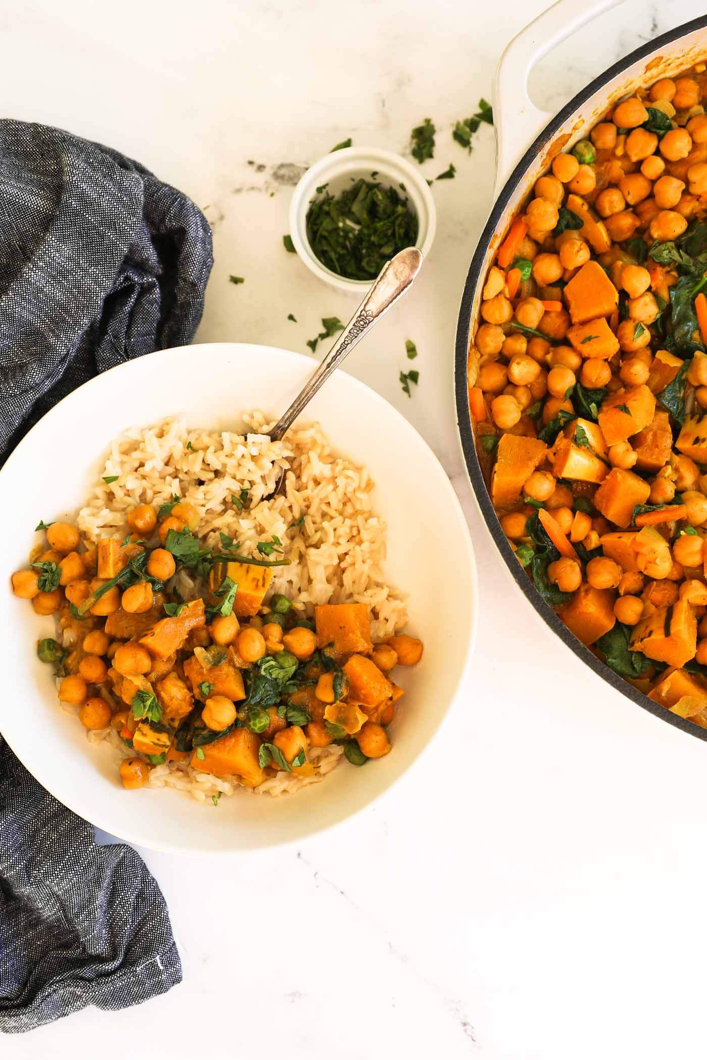 Chickpea and spinach curry served over a bowl of brown rice with chopped cilantro on top.