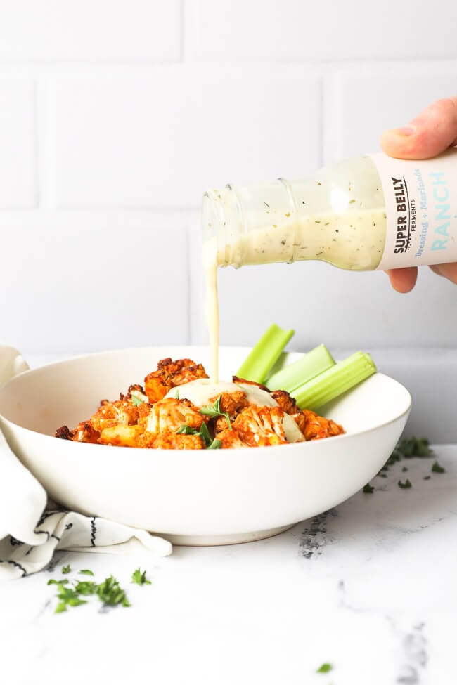Air fryer buffalo cauliflower in a bowl with ranch being poured on top