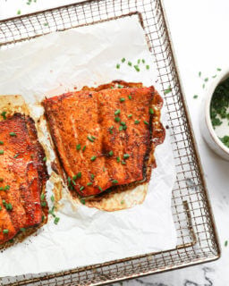 Overhead image of air fryer salmon on tray with chopped chives sprinkled on top.