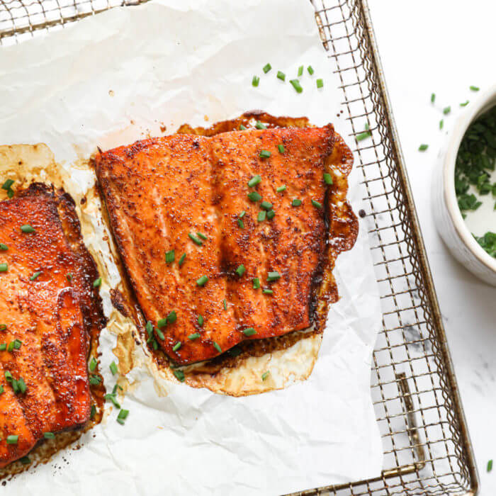 Overhead image of air fryer salmon on tray with chopped chives sprinkled on top.
