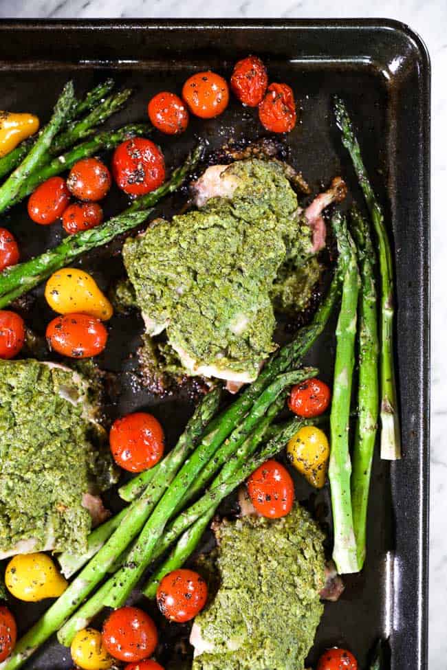 Easy baked pesto chicken on sheet pan with tomatoes and asparagus close up image