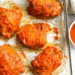 Overhead image of air fryer chicken thighs with buffalo sauce