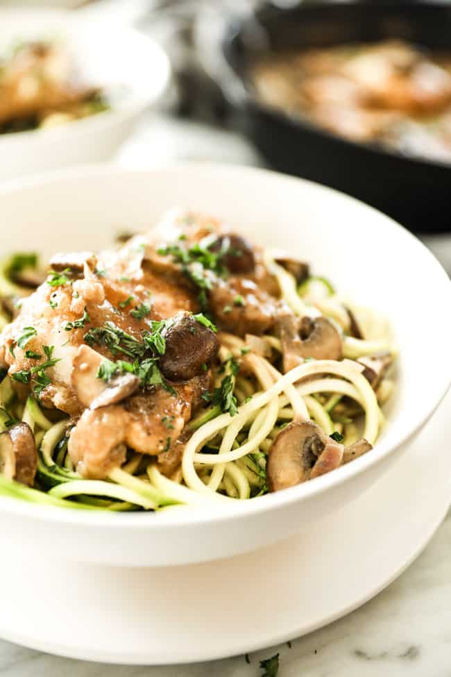 Easy chicken marsala with chicken, mushrooms and a creamy sauce served in a bowl over zucchini noodles. Fresh chopped parsley sprinkled on top. 